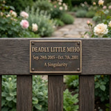 Bronze plaque with engraved text on a wooden post in a garden setting
