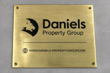 Brass plaque with Daniels Property Group logo and website on a gray background