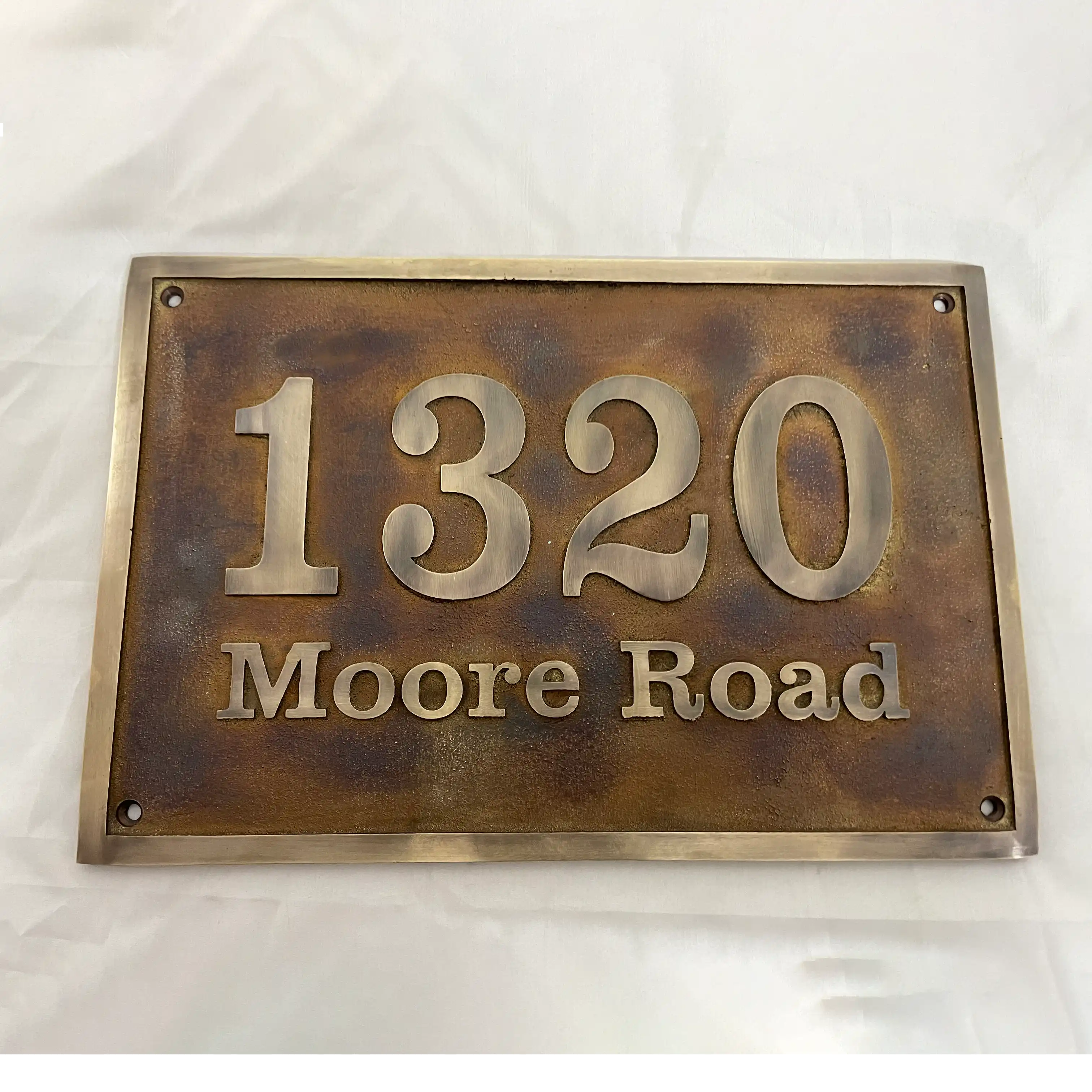 Bronze house number sign with '1320 Moore Road' on a white background