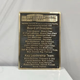 Bronze plaques for building with names and roles on a white surface and gray background