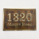 Bronze house number sign with '1320 Moore Road' on a white background