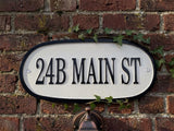 House number sign '24B MAIN ST' on a brick wall with ivy