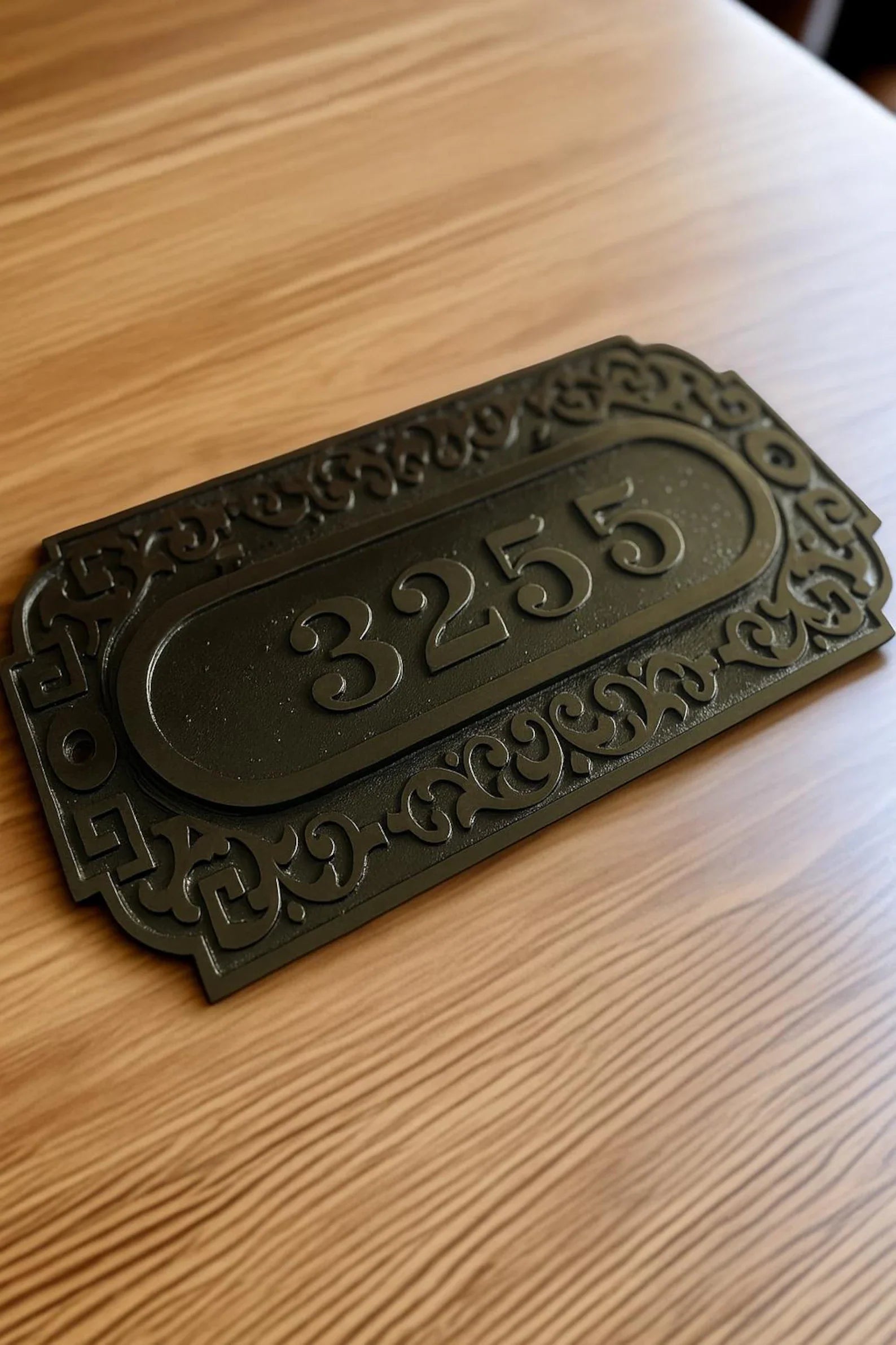 Decorative house number plate with '3255' on a wooden surface