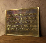 Memorial plaque for Cheryl Jennings on a wooden surface with a stone wall background