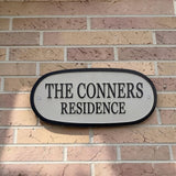 Enameled metal sign with 'The Conners Residence' on a brick wall.
