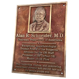 Bronze plaque with a portrait of Alan R. Schneider, M.D., and engraved text on a white background.