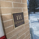 Address sign on a brick wall with 'III LEWIS DR.' text