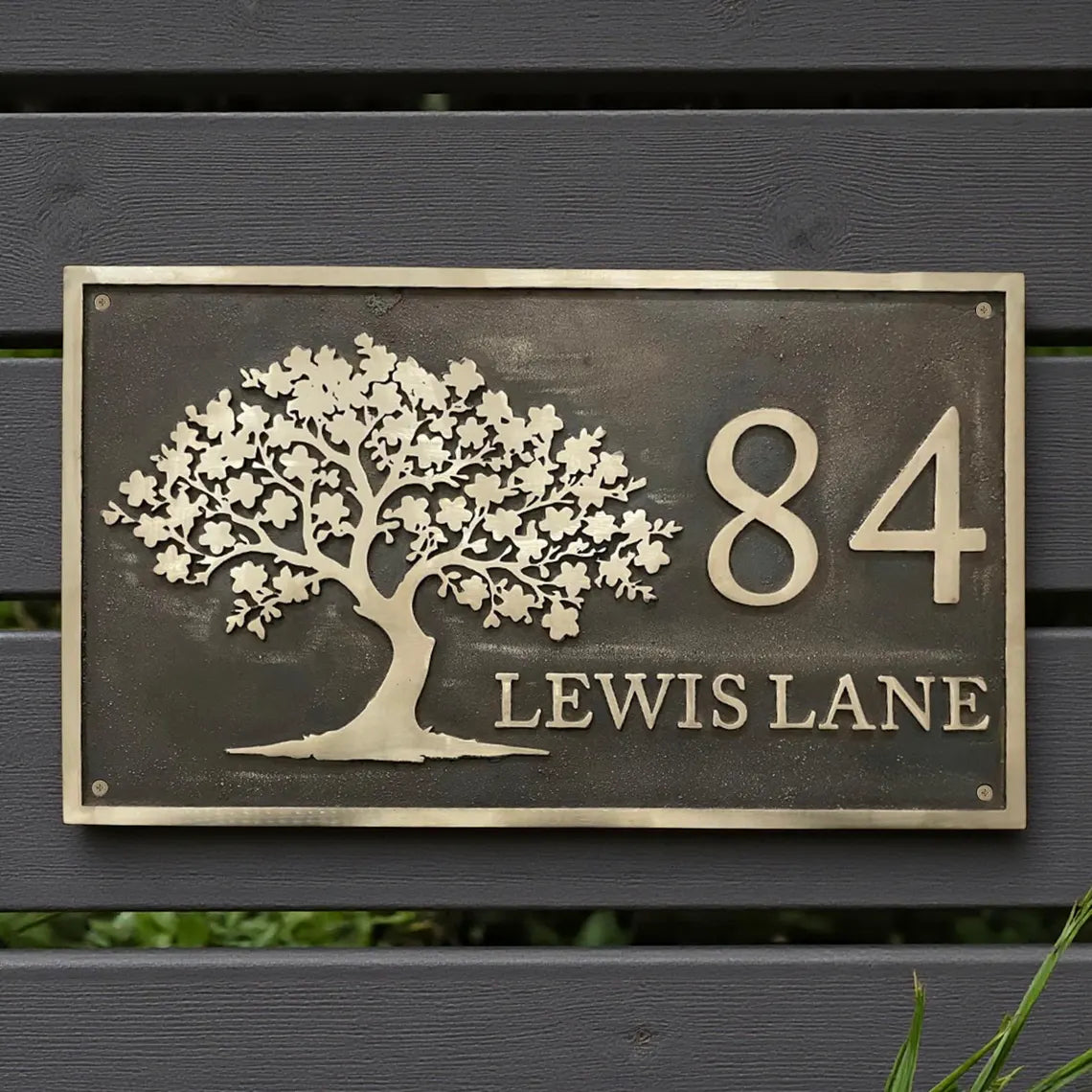 Decorative house number sign with tree design on a wooden background - handcrafted bronze house number plaque