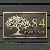 Decorative house number sign with tree design on a wooden background - handcrafted bronze house number plaque
