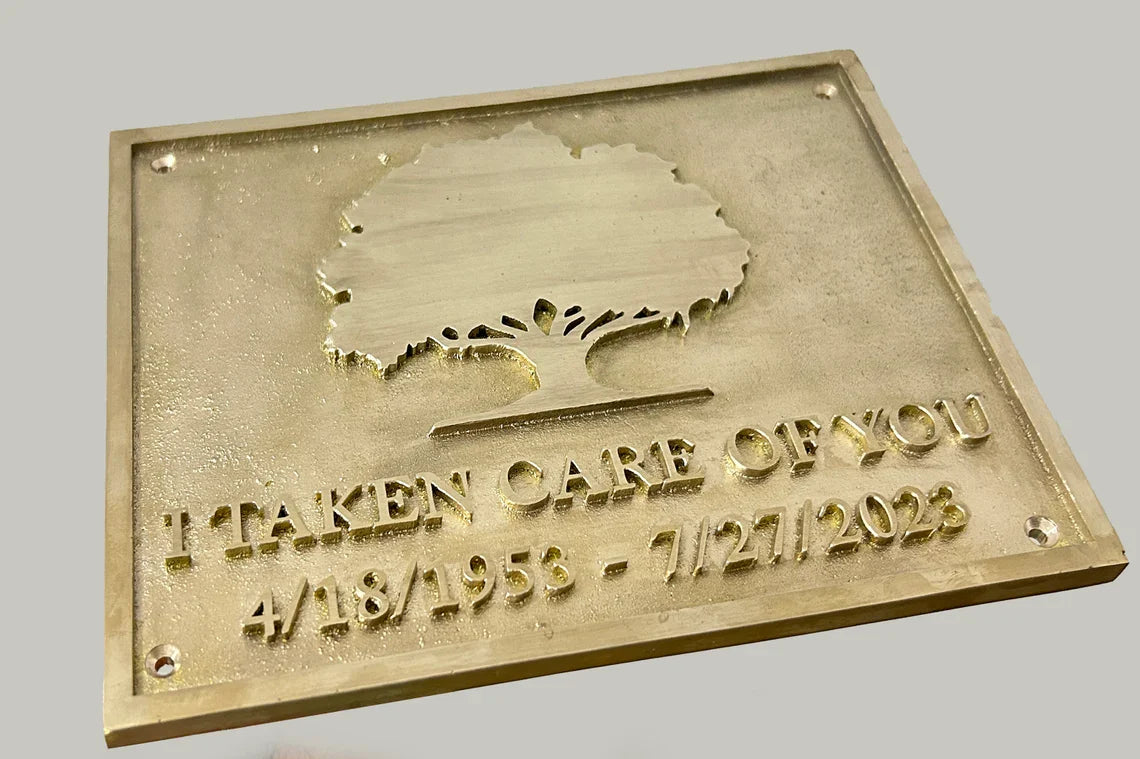 Brass plaque with engraved text and tree design on a gray background