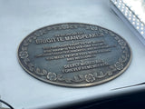 Memorial plaque on a car window honoring Brigitte Manspeaker with engraved text.