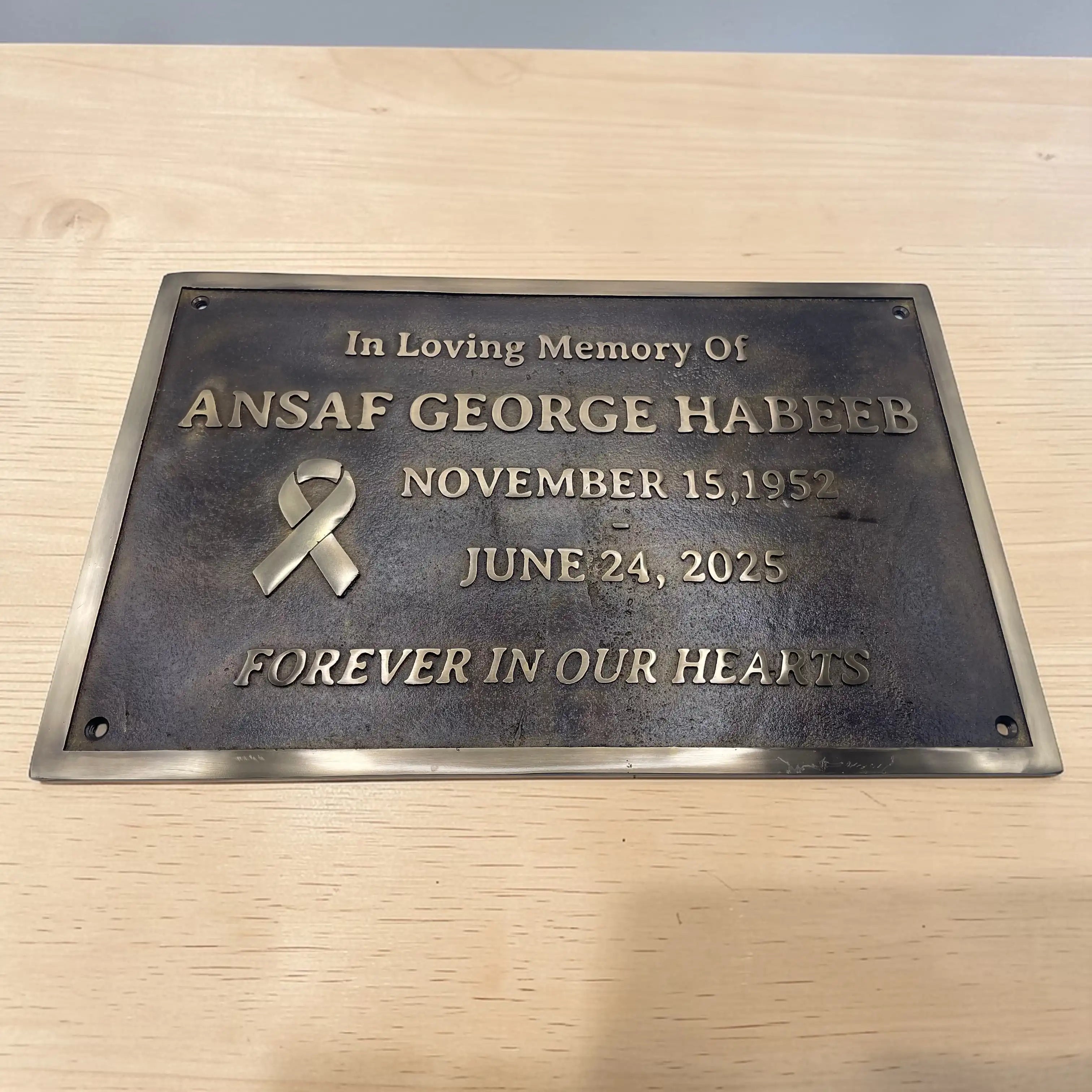 Memorial plaque for Ansaaf George Habeeb on a wooden surface
