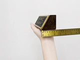 Hand holding a gold bar with a ruler for scale on a light gray background