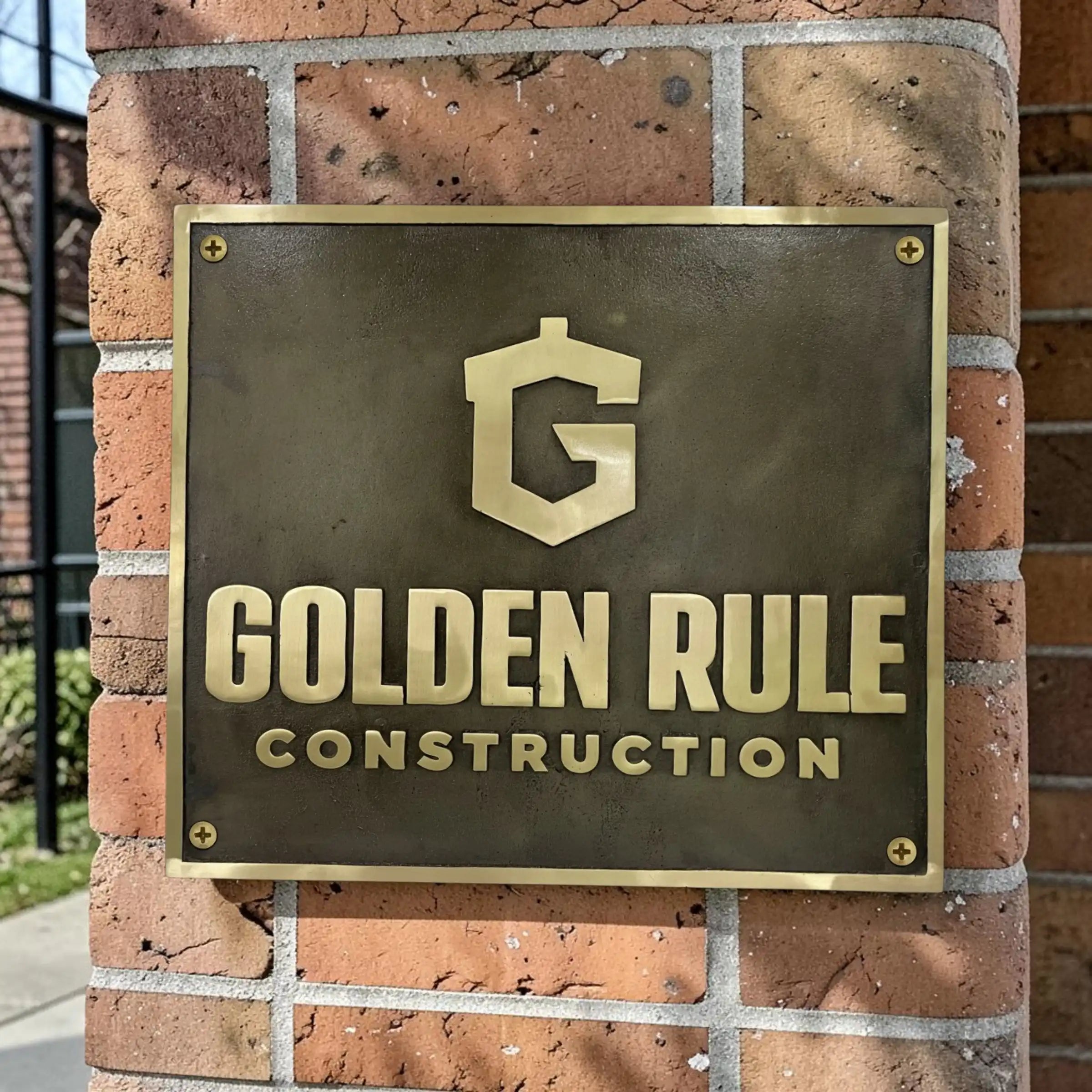 Bronze sign with 'Golden Rule Construction' logo on a white background