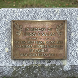 Bronze plaque on a stone wall with engraved text in memory of Terry G Salas.