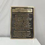 Bronze plaques for building with names and roles on a white surface and gray background