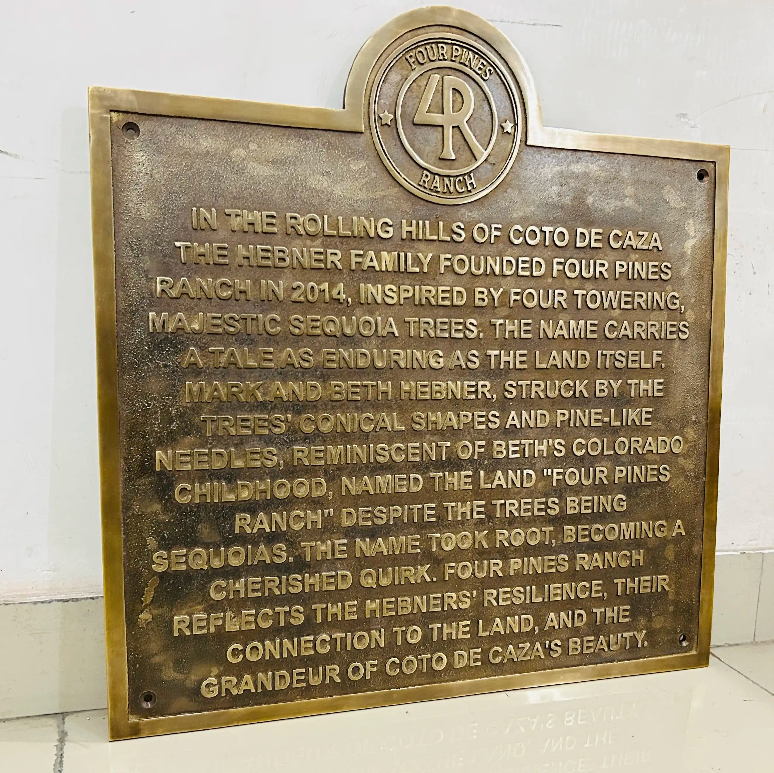 Bronze plaque with engraved text and Four Pines Ranch logo on a white background