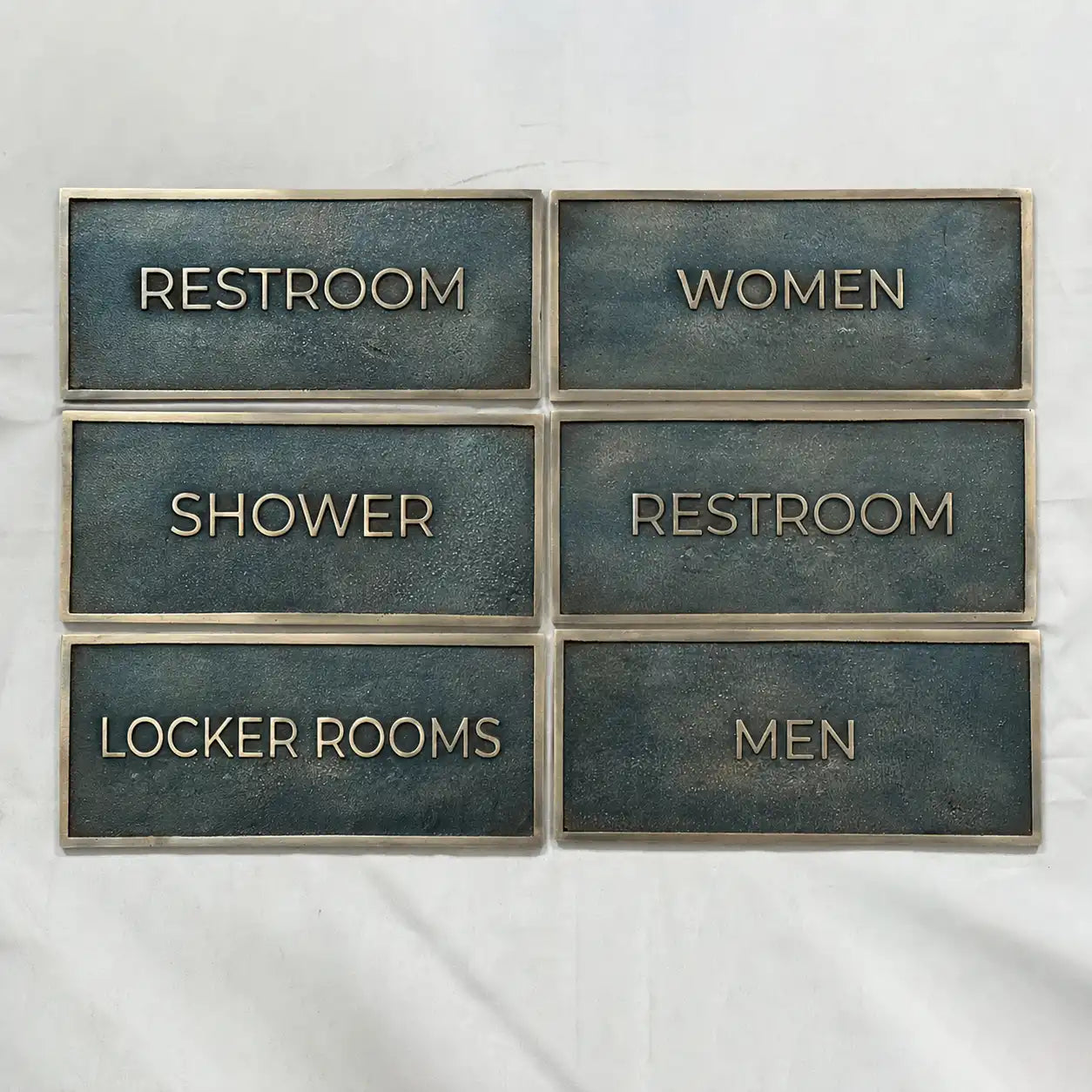 Custom antique brass door sign with raised lettering - Set of restroom signs with labels for Restroom, Women, Shower, Restroom, Locker Rooms, and Men on a white background.
