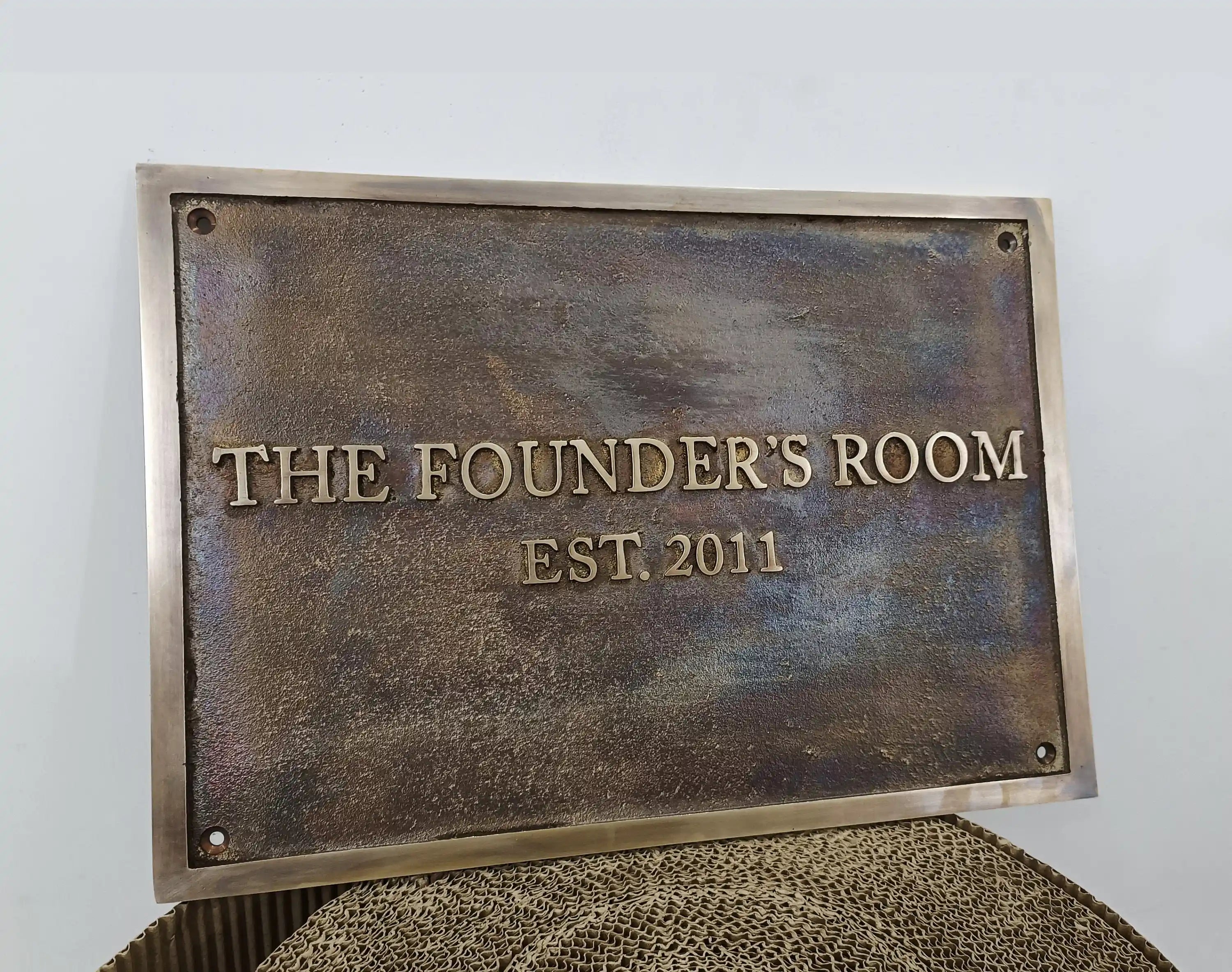 Bronze plaque with 'The Founder's Room EST. 2011' text on a gray background