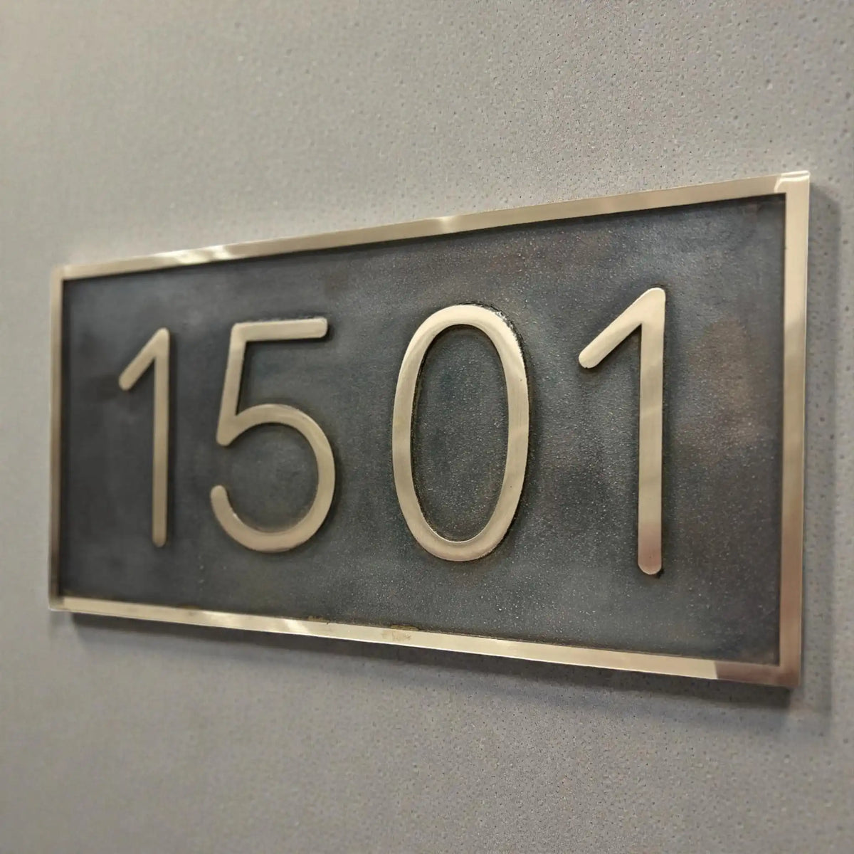 Bronze house number plaque - House number sign '1501' on a gray wall