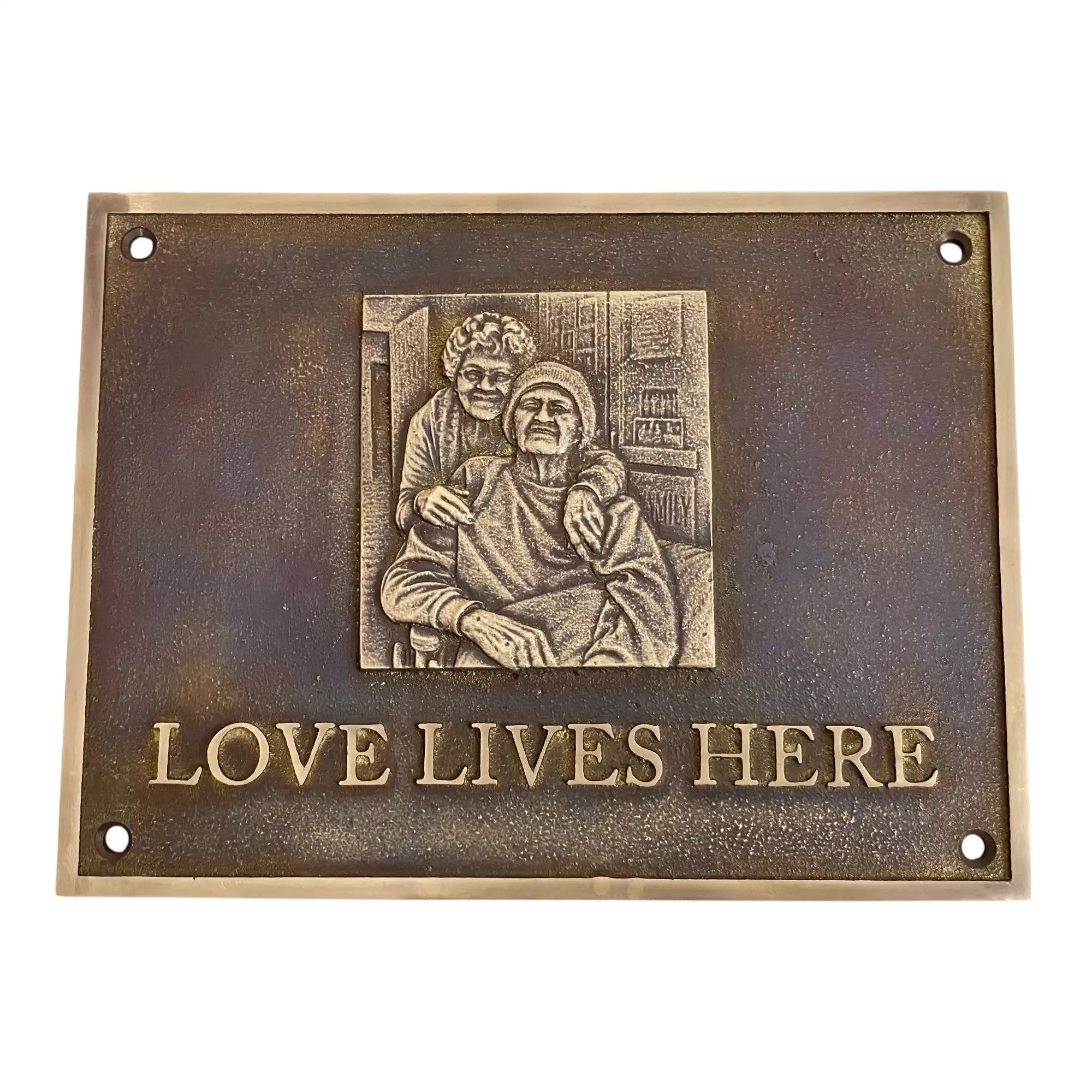 Bronze plaque with an engraving of two people and 'Love Lives Here' text on a white background
