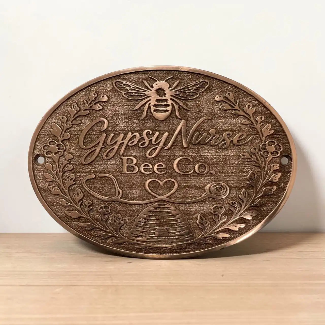 metal sign with 'Gypsy Nurse Bee Co' text and bee design on a wooden surface.