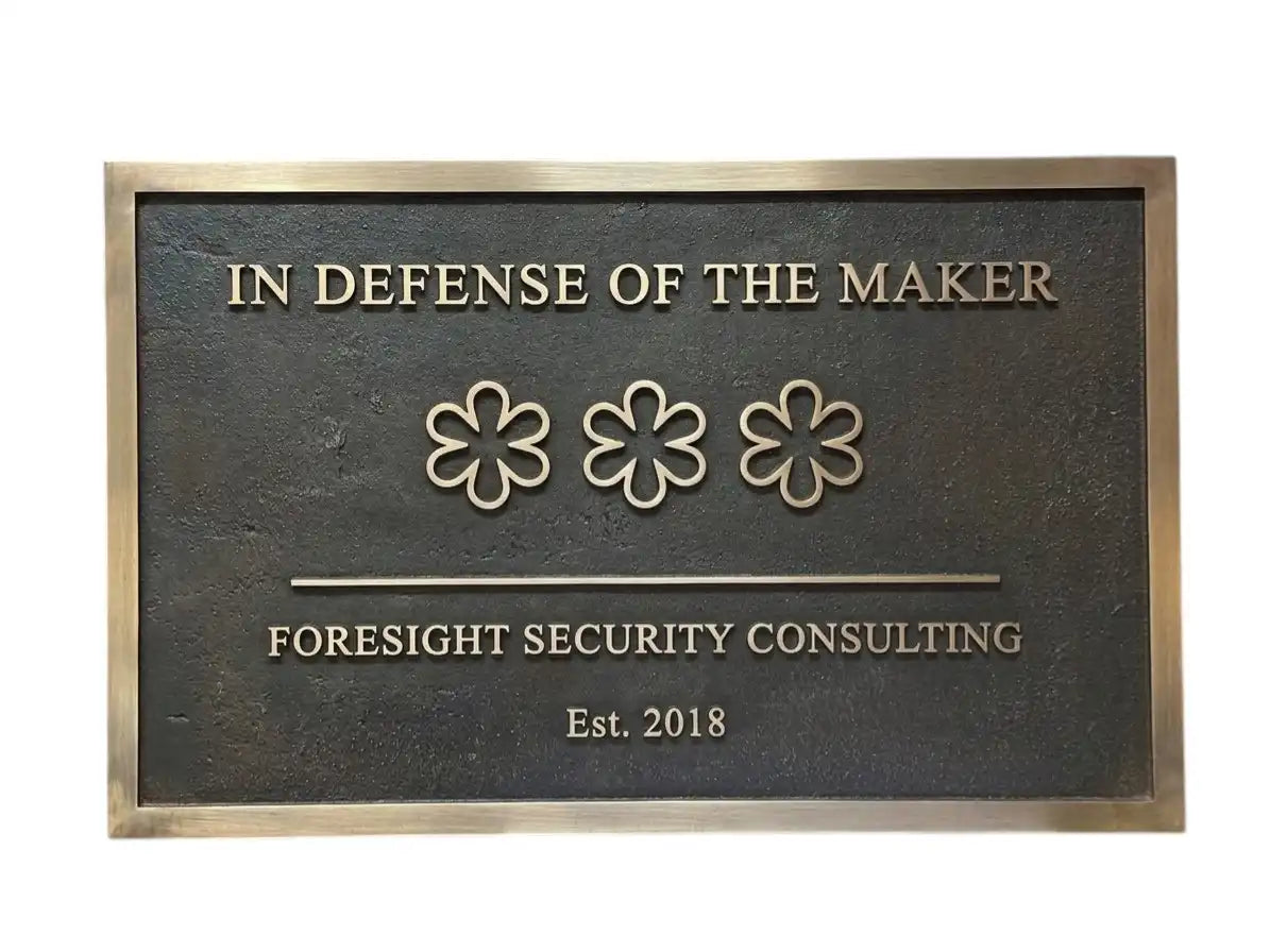 Bronze Plaque with 'In Defense of the Maker' and 'Foresight Security Consulting' text on a white background