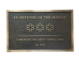 Bronze Plaque with 'In Defense of the Maker' and 'Foresight Security Consulting' text on a white background